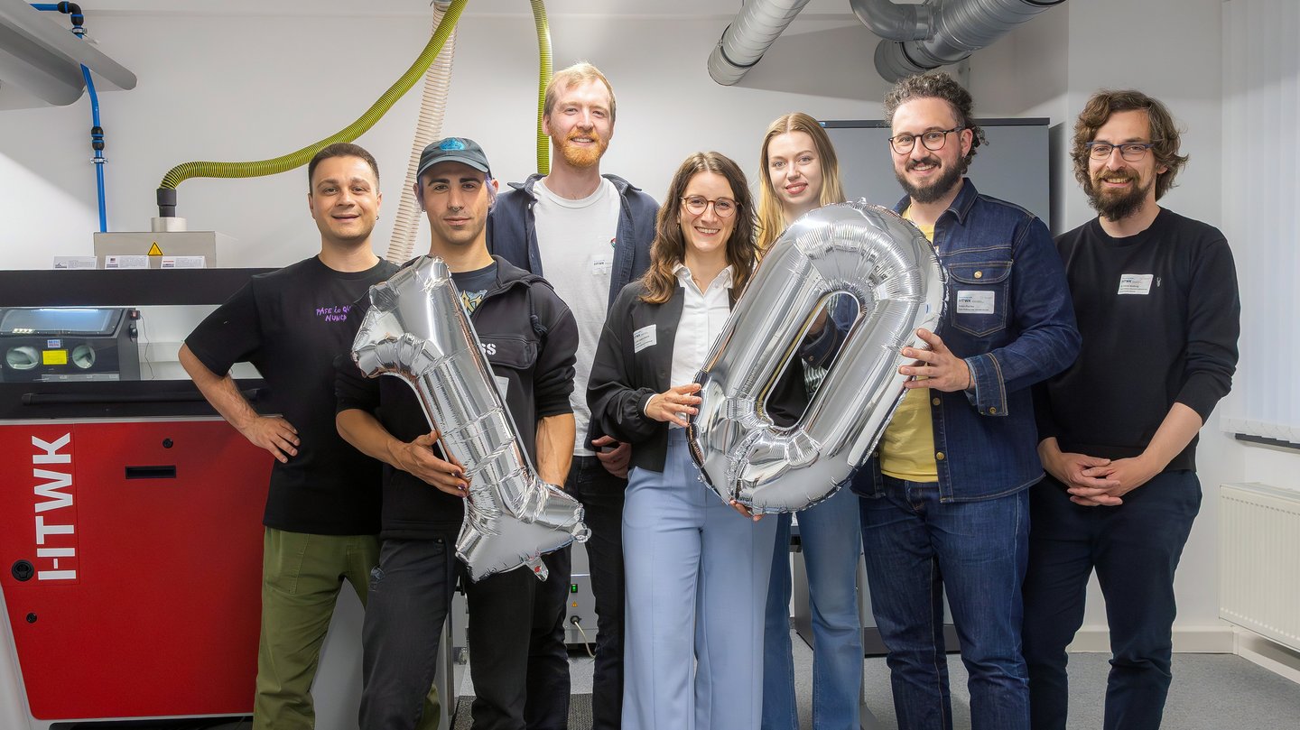 7 Personen halten eine 1 und eine 0 als Luftballon hoch