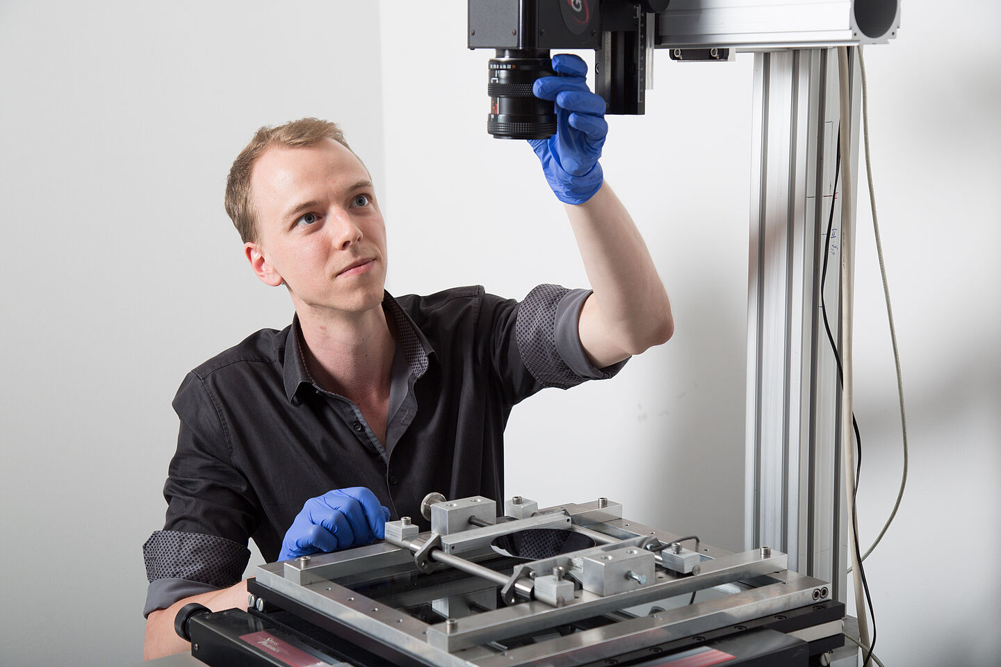 Markus Stöhr richtet das Spannungsoptik-Messgerät für die Prüfung eines Siliziumwafers ein. Polarisiertes Licht leuchtet von unten durch das Silizium, das darüber positionierte Objektiv zeichnet die Änderung der Polarisation des Lichtstrahls auf. Daraus lassen sich mechanische Spannungen im Material berechnen. 