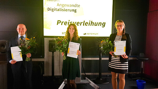 Helge Nickel, Stefanie Penzel und Zsófia Harsányi. (v.l.n.r.; Foto: Actemium) Ein Mann und zwei Frauen auf einer Bühne, sie erhalten Preise.