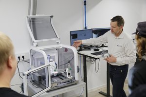 Mann zeigt anderen Personen 3D-Drucker