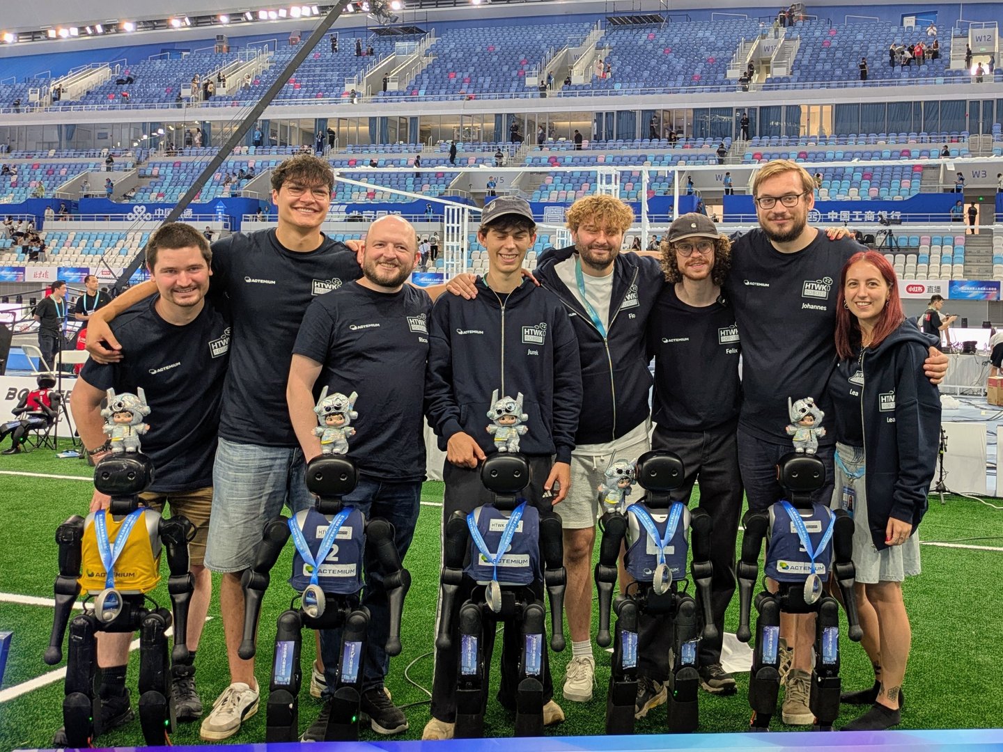 Gruppenbild von Menschen und humanoiden Robotern in Stadion