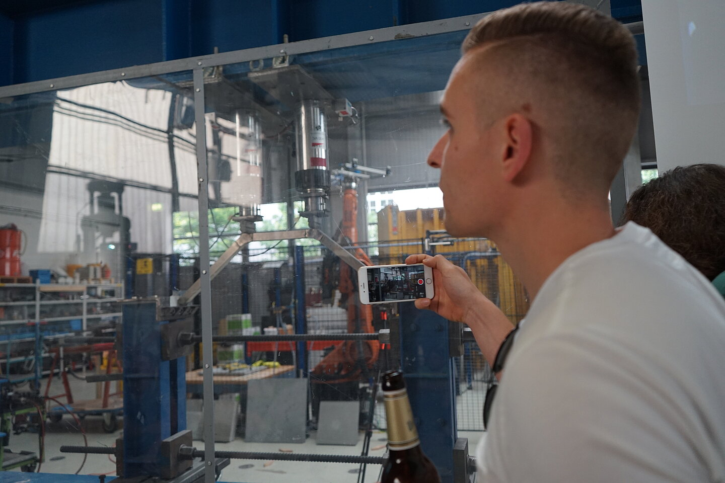 Das Gewinnermodell: Germo Ratz nimmt Videobeweis seines Sieges auf Germo nimmt mit dem Handy in der einen und Bierflasche in der anderen Hand ein Video seiner Brücke im Versuchsapparat auf.