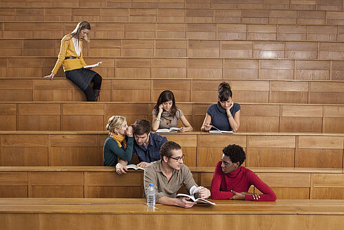 Sieben Studierende sitzen im Hörsaal und unterhalten sich